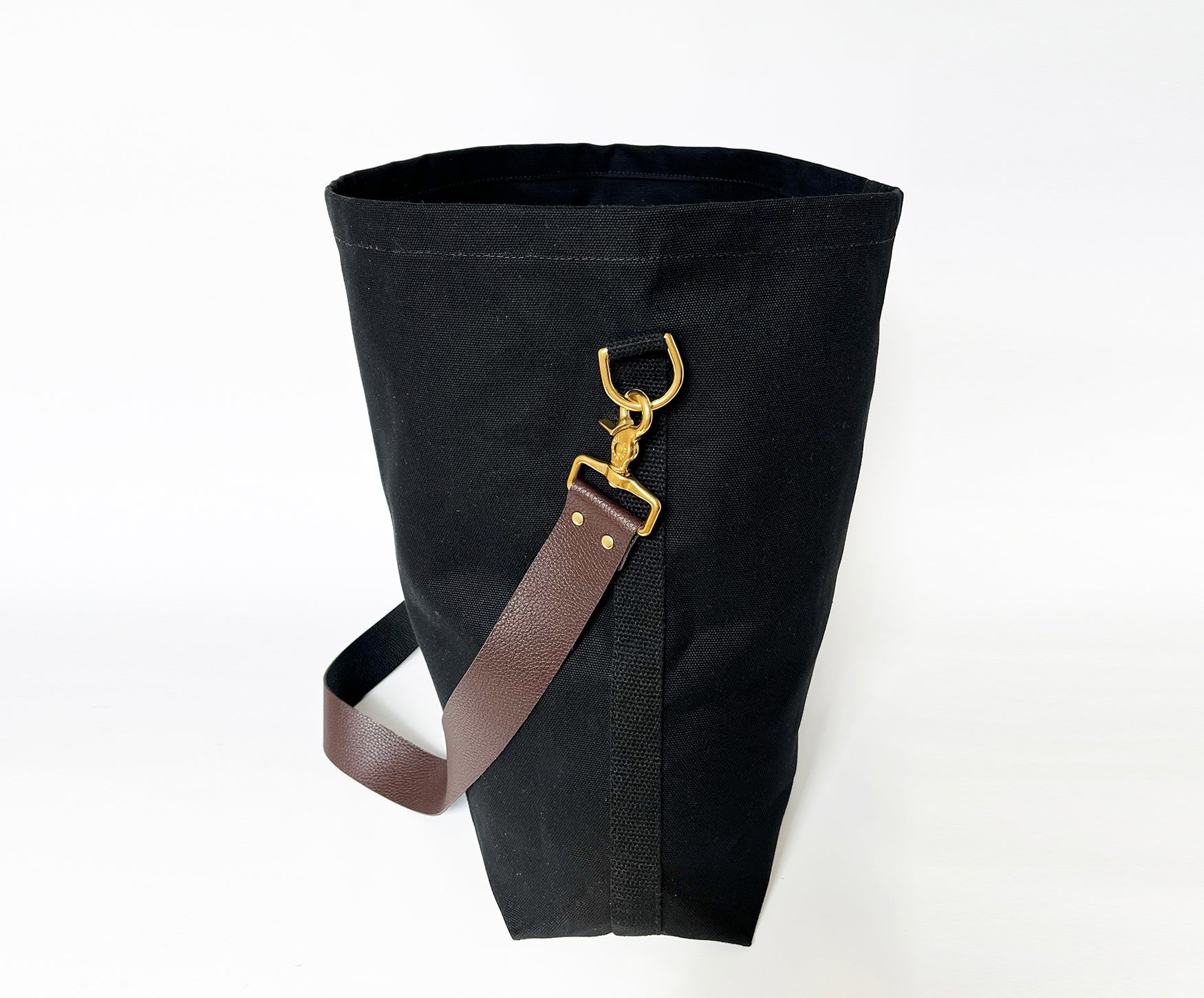 Black bag with a brown strap and gold buckle on a white background
